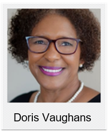 Portrait of Doris Vaughans, smiling woman with short curly hair, blue-framed glasses, and a pearl necklace.